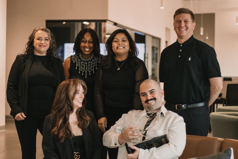 A diverse team of real estate professionals collaborates around a table in a modern, bright office, showcasing the combined expertise available for an Orlando home sale.