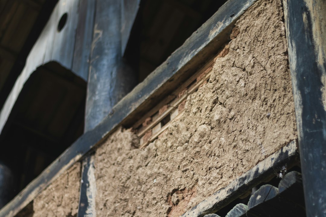A contractor in protective gear expertly applies spray foam insulation to the underside of a roof, showing the professional solution to attic heat gain.